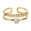 The golden double-layered ring features multiple round transparent gemstones on the upper layer and a large round transparent gemstone in the center on the lower layer. It has a white stone countertop Item Picture